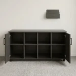4-door wooden office cupboard featuring a dark charcoal grey wood grain finish, four hinged swing doors with sleek black vertical handles, a low-profile credenza silhouette, internal divided shelving units, and a mobile base equipped with heavy-duty caster wheels.