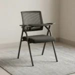 Foldable chair with writing pad featuring a breathable black mesh backrest, a cushioned dark grey fabric seat, integrated armrests, a built-in foldaway writing tablet with a cup holder, and a space-saving foldable black tubular steel frame.