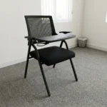 Foldable chair with writing pad featuring a breathable black mesh backrest, a cushioned dark grey fabric seat, integrated armrests, a built-in foldaway writing tablet with a cup holder, and a space-saving foldable black tubular steel frame.