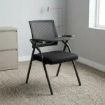 Foldable chair with writing pad featuring a breathable black mesh backrest, a cushioned dark grey fabric seat, integrated armrests, a built-in foldaway writing tablet with a cup holder, and a space-saving foldable black tubular steel frame.