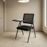 Foldable chair with writing pad featuring a breathable black mesh backrest, a cushioned dark grey fabric seat, integrated armrests, a built-in foldaway writing tablet with a cup holder, and a space-saving foldable black tubular steel frame.