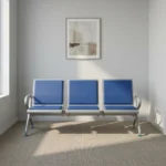 Heavy duty blue waiting bench featuring a 3-seater design with cushioned royal blue leatherette seat and back pads, a silver powder-coated steel frame, integrated side armrests, and a sturdy beam structure supported by slanted legs with leveling glides.