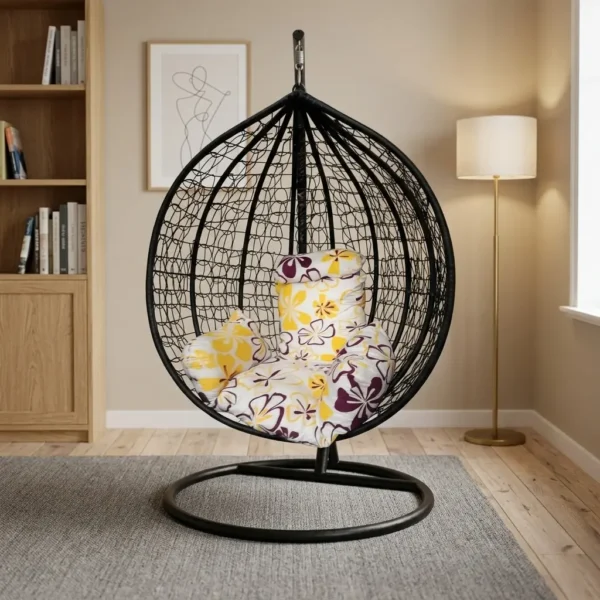 Outdoor hammock swing featuring a spherical black woven resin wicker basket chair suspended from a heavy-duty black steel stand with a circular base, fitted with plush floral-patterned yellow and purple seating cushions.