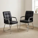 Modern black leather visitor chair featuring plush grid-tufted black leatherette upholstery, fixed armrests with black padded arm pads, and a sleek chrome cantilever sled frame.