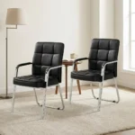 Modern black leather visitor chair featuring plush grid-tufted black leatherette upholstery, fixed armrests with black padded arm pads, and a sleek chrome cantilever sled frame.