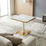 Modern square dining table featuring a white faux marble top with polished gold metallic edging, supported by a central white tulip pedestal column and a heavy flat square brass-toned base.