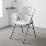Heavy duty white foldable chair featuring a blow-molded high-density white plastic seat and backrest with a decorative fan motif and built-in carrying handle, supported by a sturdy powder-coated grey steel folding frame with cross-bracing and non-marring foot caps.