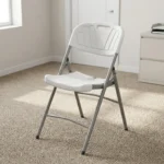 Heavy duty white foldable chair featuring a blow-molded high-density white plastic seat and backrest with a decorative fan motif and built-in carrying handle, supported by a sturdy powder-coated grey steel folding frame with cross-bracing and non-marring foot caps.