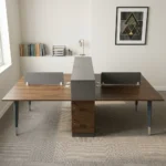 Wooden 4-seater workstation desk featuring rich dark walnut wood tabletops, a central grey storage divider spine with lower lockable pedestal drawers, side privacy desktop screens, integrated wire grommets, and sturdy grey metallic support legs with silver accents.