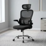Ergonomic chair with flip armrests featuring a breathable black mesh backrest, an adjustable mesh headrest, integrated lower lumbar support cushion, padded fabric seat, 90-degree flip-up padded armrests, height adjustment lever, and a chrome five-star swivel base with caster wheels.