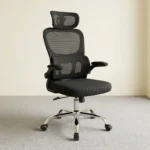 Ergonomic chair with flip armrests featuring a breathable black mesh backrest, an adjustable mesh headrest, integrated lower lumbar support cushion, padded fabric seat, 90-degree flip-up padded armrests, height adjustment lever, and a chrome five-star swivel base with caster wheels.