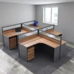 4-seater curved workstation featuring a quad L-shaped pod layout with teak wood-grain tabletops, dark grey side panels and modesty boards, semi-private divider screens with frosted slatted glass panels, and individual lockable under-desk mobile pedestal drawer units.