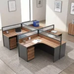 4-seater curved workstation featuring a quad L-shaped pod layout with teak wood-grain tabletops, dark grey side panels and modesty boards, semi-private divider screens with frosted slatted glass panels, and individual lockable under-desk mobile pedestal drawer units.