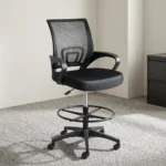 Black ergonomic cashier chair featuring a breathable black mesh backrest with built-in lumbar support, a padded fabric seat cushion, curved fixed armrests, height adjustment lever, an adjustable circular chrome foot ring, and a five-star nylon swivel base with caster wheels.