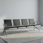 4-seater airport bench featuring four contoured seats with black padded faux leather cushions, silver powder-coated steel frames, curved metallic end armrests, and a heavy-duty beam structure supported by angled metal legs.
