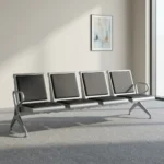 4-seater airport bench featuring four contoured seats with black padded faux leather cushions, silver powder-coated steel frames, curved metallic end armrests, and a heavy-duty beam structure supported by angled metal legs.