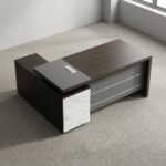 1.6 meters L-shaped executive desk featuring a dark espresso wood-grain finish, a matte grey desktop extension panel with an integrated flip-up cable grommet, a front modesty panel with horizontal grey accents, and an attached side return cabinet with three white faux-marble front lockable drawers and open storage shelving.
