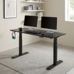 Electric height adjustable table featuring a spacious matte black rectangular desktop, digital push-button LED keypad controller, integrated side accessory headphone hook, motorized dual telescoping steel lifting columns, and a heavy-duty black steel T-frame base.