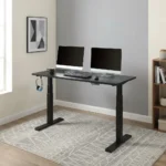 Electric height adjustable table featuring a spacious matte black rectangular desktop, digital push-button LED keypad controller, integrated side accessory headphone hook, motorized dual telescoping steel lifting columns, and a heavy-duty black steel T-frame base.