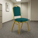 Stackable green conference chair featuring diamond-patterned emerald green upholstered fabric with subtle white dot accents, a cushioned crown-back seat and backrest, top integrated handle grip, and a sturdy metallic gold-painted steel frame with protective floor glides.