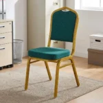 Stackable green conference chair featuring diamond-patterned emerald green upholstered fabric with subtle white dot accents, a cushioned crown-back seat and backrest, top integrated handle grip, and a sturdy metallic gold-painted steel frame with protective floor glides.
