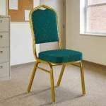 Stackable green conference chair featuring diamond-patterned emerald green upholstered fabric with subtle white dot accents, a cushioned crown-back seat and backrest, top integrated handle grip, and a sturdy metallic gold-painted steel frame with protective floor glides.