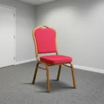 Stackable red conference chair featuring diamond-patterned bright red upholstered fabric with subtle white dot accents, a cushioned crown-back seat and backrest, top integrated handle grip, and a sturdy metallic gold-painted steel frame with non-marring floor glides.