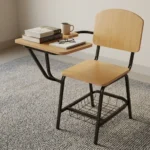 Wooden student study chair featuring light natural oak plywood seat and backrest panels, an attached right-hand tablet writing desk with rounded corners, a tubular black metal frame, and an under-seat wire mesh book basket.