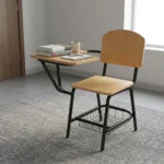 Wooden student study chair featuring light natural oak plywood seat and backrest panels, an attached right-hand tablet writing desk with rounded corners, a tubular black metal frame, and an under-seat wire mesh book basket.