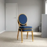 Armless blue conference chair featuring navy blue fabric upholstery with white dot pattern, a oval medallion backrest, a cushioned seat, and a stackable gold-finished metal frame with straight legs and floor glides.