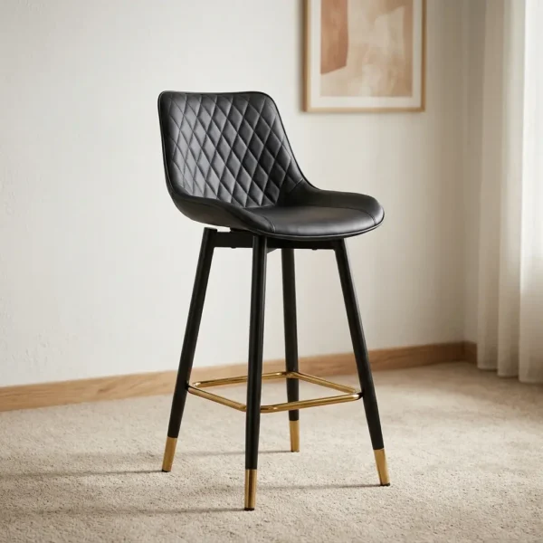 Black leather counter barstool featuring diamond-quilted faux leather upholstery on the backrest, a smooth contoured bucket seat, black tapered legs with brass-finished foot caps, and a metallic gold square footrest ring.