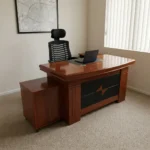 1.6m executive office table featuring a warm reddish-brown wood-grain finish, an inlaid black leather writing pad, integrated dual cable management grommets, an attached side return credenza, a mobile low-profile pedestal cabinet, and a decorative black and wood-tone diamond-pattern front modesty panel.