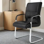 Black leather visitor seat featuring supple black leatherette upholstery with stitched paneling and plush padding, fixed armrests with black protective pads, and a polished chrome-finished cantilever sled base frame.