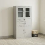 Steel cabinet with safe featuring a powder-coated light grey finish, a top double-door glass display cabinet with key lock, a middle section with three drawers alongside a locked safe compartment, and a bottom double steel-door storage locker with key lock.