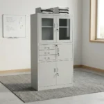 Steel cabinet with safe featuring a powder-coated light grey finish, a top double-door glass display cabinet with key lock, a middle section with three drawers alongside a locked safe compartment, and a bottom double steel-door storage locker with key lock.