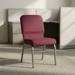 Fabric stackable church chair featuring plush burgundy fabric upholstery with a padded rectangular backrest and waterfall seat design, an armless ergonomic profile, an under-seat metal wire book rack, and a durable silver powder-coated steel frame with protective floor glides.