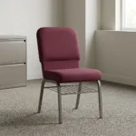 Fabric stackable church chair featuring plush burgundy fabric upholstery with a padded rectangular backrest and waterfall seat design, an armless ergonomic profile, an under-seat metal wire book rack, and a durable silver powder-coated steel frame with protective floor glides.