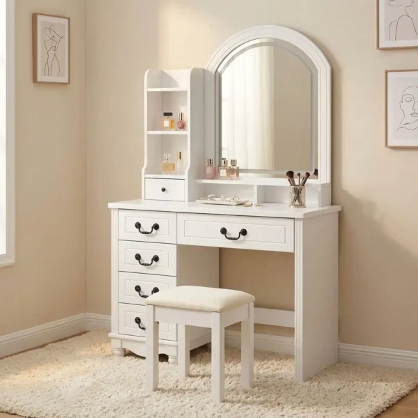 Vanity dressing table with LED featuring a matte white wood finish, an arched vanity mirror with integrated halo LED lighting, an attached side hutch with open display shelves and a small organizer drawer, five main storage drawers with dark vintage-style bail pull handles, and a matching cushioned vanity stool with white wood legs.
