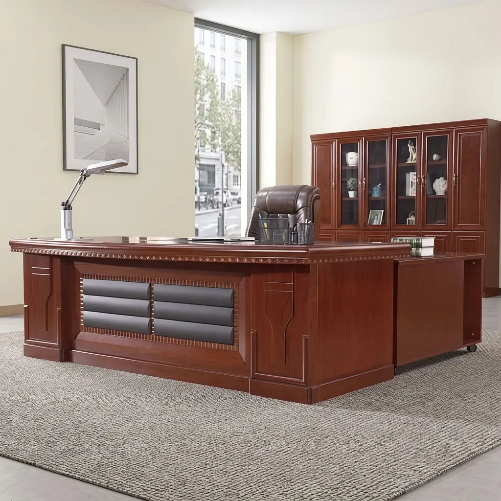 2m mahogany executive desk featuring a premium mahogany wood veneer finish with intricate carved trim detailing, a recessed front modesty panel with horizontal black leatherette padding, an integrated side return cabinet on caster wheels, built-in wire management ports, and heavy-duty box pedestal supports.