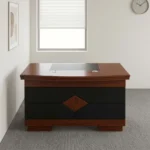 1.2m classic executive desk featuring a rich mahogany wood-veneer finish, a curved-front main desk surface with an inset black leatherette writing pad, dual circular cable management grommets, a front modesty panel detailed with black leatherette panels and a central diamond wood inlay, and a solid wooden plinth base.
