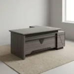 Executive 2.0m L-shaped office desk featuring a dark grey wood-grain laminate finish, dual flip-top desktop cable management grommets, a stylized front modesty panel with black geometric accent detailing, a integrated side return extension unit with drawer storage, and solid panel-style engineered wood base supports.