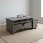 Executive 2.0m L-shaped office desk featuring a dark grey wood-grain laminate finish, dual flip-top desktop cable management grommets, a stylized front modesty panel with black geometric accent detailing, a integrated side return extension unit with drawer storage, and solid panel-style engineered wood base supports.