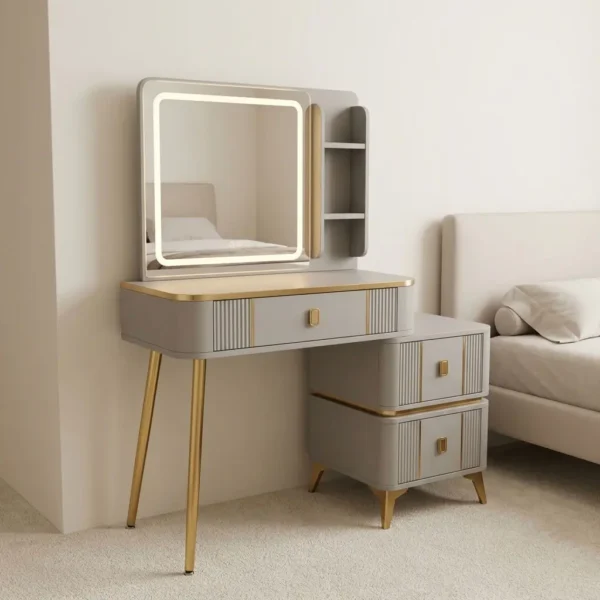 Dresser table with lighted mirror featuring a smooth off-white finish with fluted detail panels and brushed gold trim, an integrated square LED illuminated mirror with touch-sensor control alongside side display shelving, a main vanity table with a central storage drawer, an attached side chest with two additional storage drawers accented by gold hardware handles, and splayed brushed gold steel support legs.