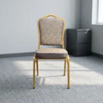 Comfortable armless fabric conference chair featuring patterned beige fabric upholstery over a thick padded seat cushion and backrest, an armless stackable crown-back frame design with an integrated top hand-hold handle, and a durable gold powder-coated square steel four-legged base.
