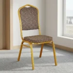 Fabric conference event chair featuring patterned beige fabric upholstery over a thick padded seat cushion and backrest, an armless stackable crown-back frame design with an integrated top hand-hold handle, and a durable gold powder-coated square steel four-legged base.
