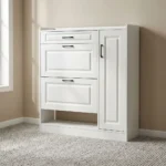 White modern shoe rack featuring crisp white engineered wood with traditional recessed panel detailing, a top utility pull-out drawer, two tilt-down shoe compartment drawers, a tall side cabinet door with slim black handles, an open lower shoe storage shelf, and a flat plinth base.
