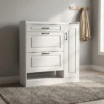 White modern shoe rack featuring crisp white engineered wood with traditional recessed panel detailing, a top utility pull-out drawer, two tilt-down shoe compartment drawers, a tall side cabinet door with slim black handles, an open lower shoe storage shelf, and a flat plinth base.