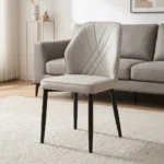 Modern leather dining chair featuring light gray faux leather upholstery with fan-style accent stitching on the inner backrest, a padded bucket-style seat with subtle side curves, an armless profile, and slim tapered black powder-coated metal legs.
