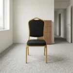 Black stackable event chair featuring black patterned fabric upholstery with gold dot accents on a crown-back backrest and padded seat cushion, an armless space-saving frame, and a durable gold powder-coated aluminum steel tubular frame base with stack bumpers and floor glides.