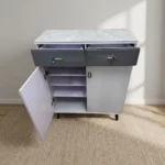 Modern bucket flip shoe rack featuring a faux grey marble top surface, two top grey lockable drawers with gold pull handles, lower dual white hinged doors opening to multi-tiered shoe storage shelves, and elevated dark tapered wooden legs.